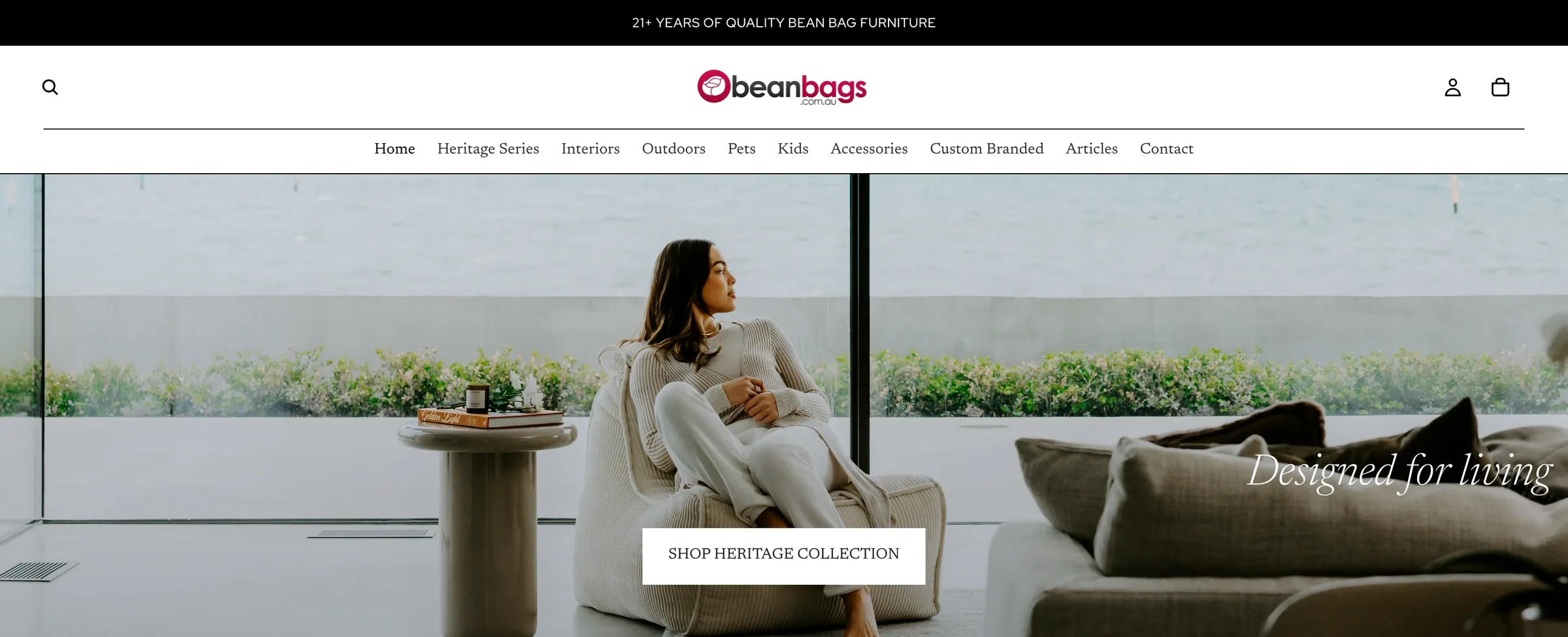 Beanbags.com.au homepage on desktop: a woman relaxing in a bean bag chair by a window over the sea, with a Shop Heritage Collection button